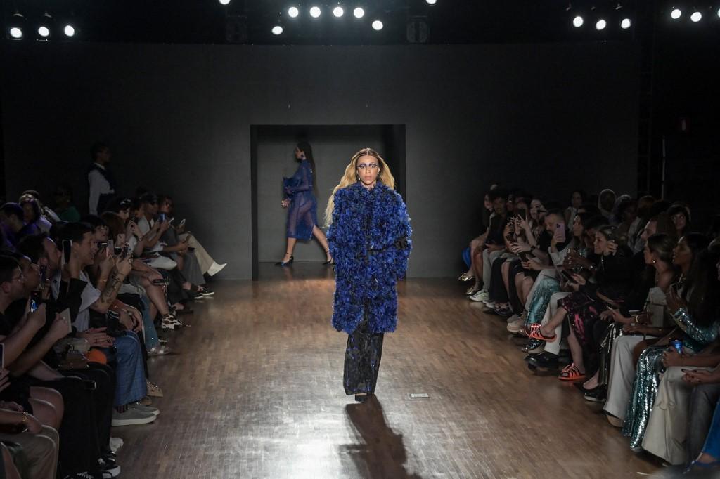 Hilton caminhou pela passarela vestindo um volumoso casaco azul-marinho e cal&ccedil;as do mesmo tom