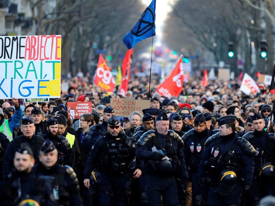 Polícia de choque da CRS anda à frente dos manifestantes que protestam contra o plano do governo francês de rever o sistema de aposentadoria do país em Paris. Polícia de choque da CRS anda à frente dos manifestantes que protestam contra o plano do governo francês de rever o sistema de aposentadoria do país em Paris.