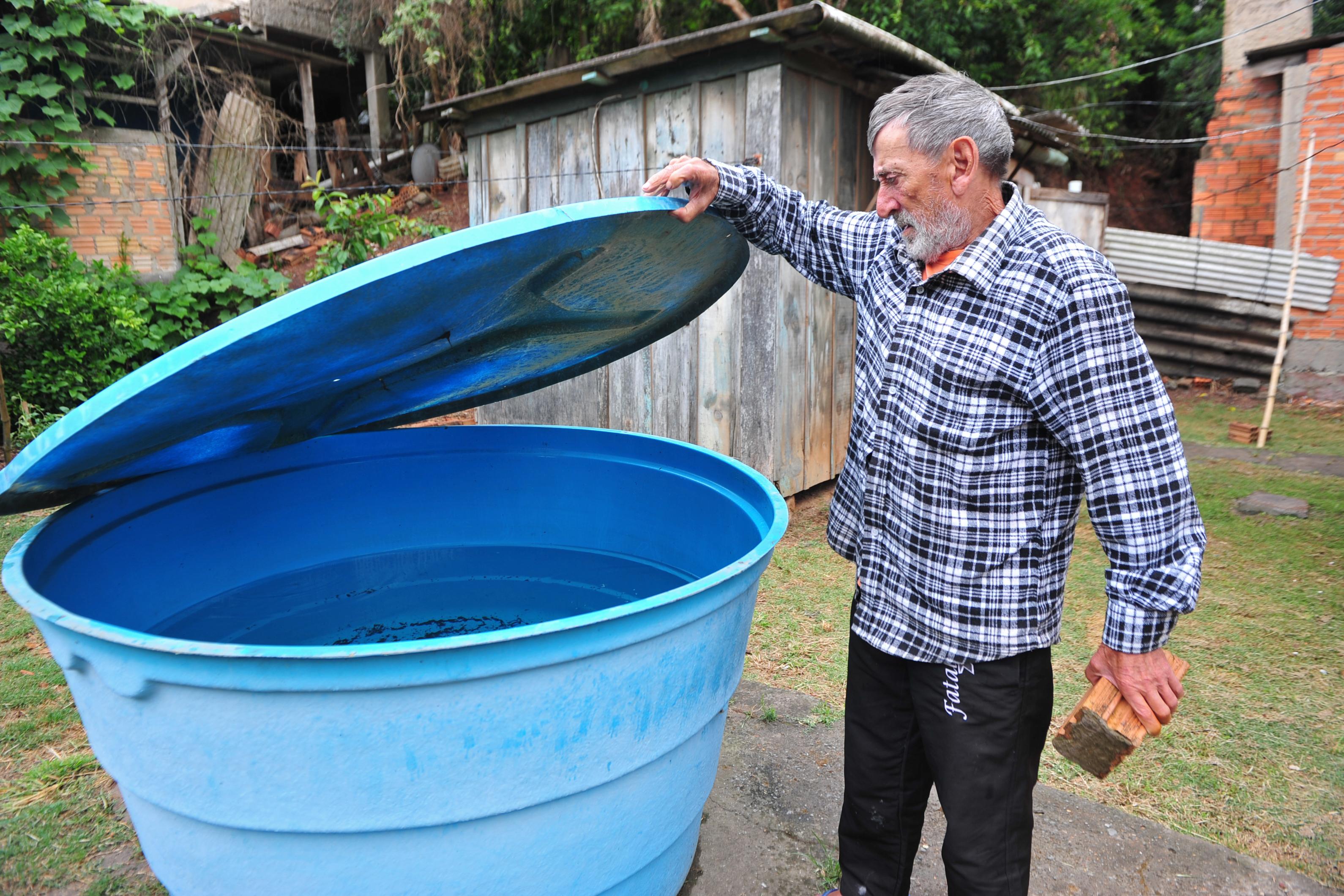 Juarez Flores, morador do bairro Aberta dos Morros, em Porto Alegre, armazena &aacute;gua doada por amigos em um reservat&oacute;rio envelhecido.