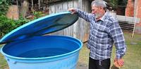 Juarez Flores, morador do bairro Aberta dos Morros, em Porto Alegre, armazena água doada por amigos em um reservatório envelhecido.