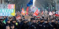 Polícia de choque da CRS anda à frente dos manifestantes que protestam contra o plano do governo francês de rever o sistema de aposentadoria do país em Paris.