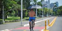 Ciclista passou pela ciclovia carregando um guarda-chuva aberto enquanto pedalava